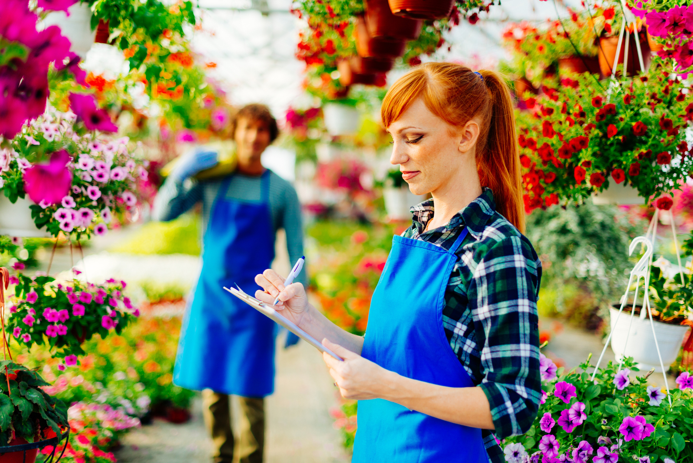 Female gardener taking orders for potted flowers delivery